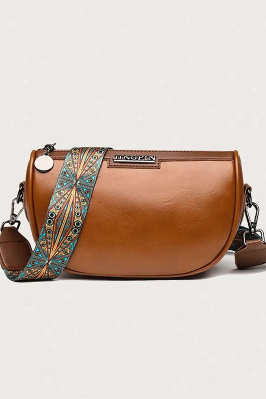 Side view of brown crescent crossbody bag, PU leather handbag with adjustable patterned strap
