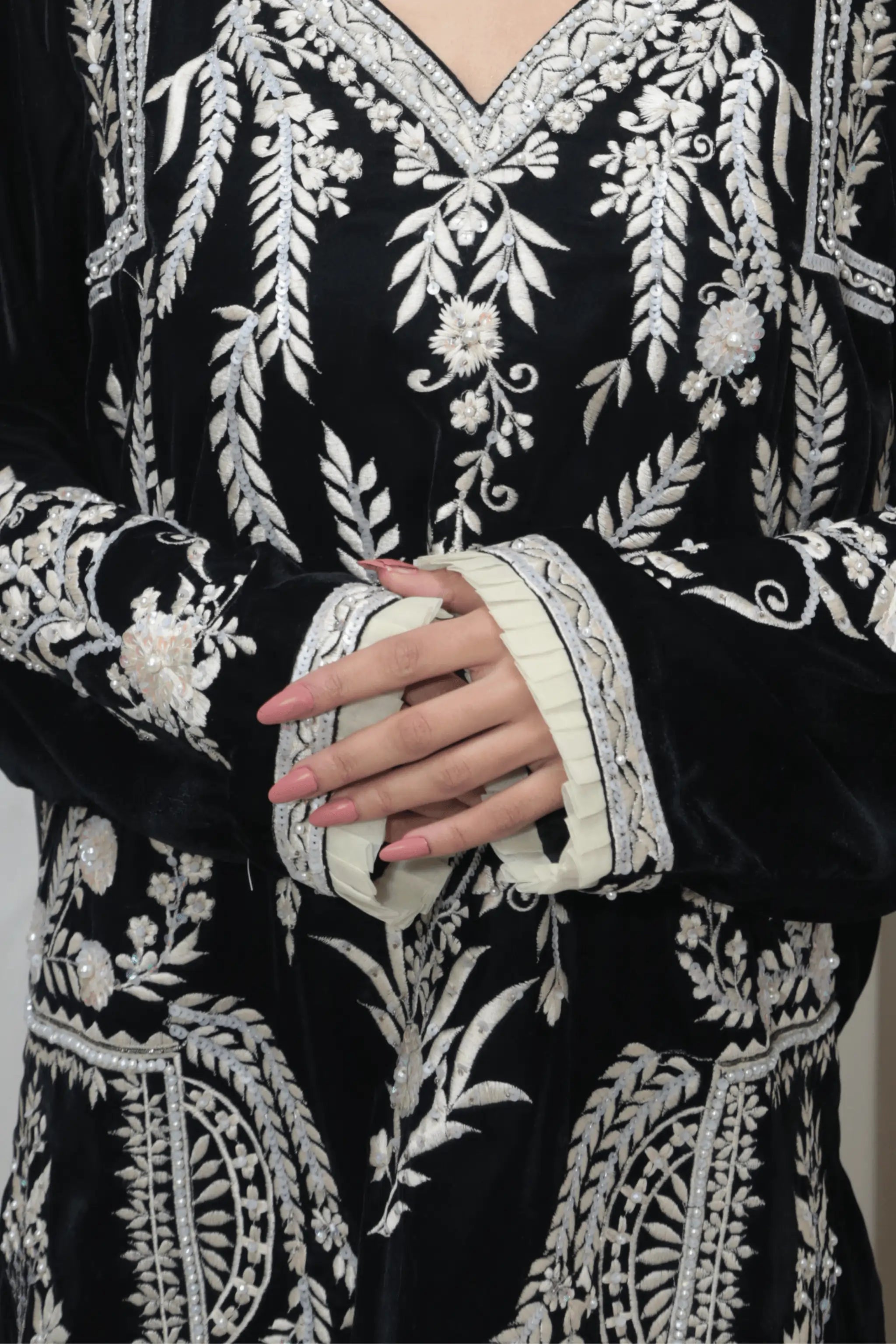 Close-up of detailed embroidery with beads, sequins, and pearls on black velvet shirt.